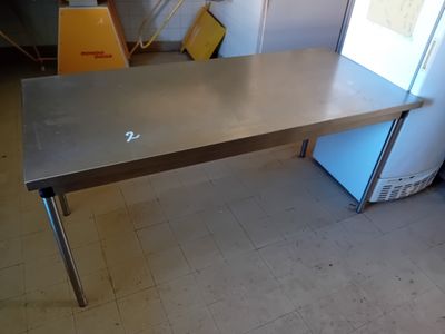 une table en acier inoxydable dans une pièce équipée d'un réfrigérateur
