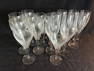 six verres à vin transparents sont alignés sur une surface noire