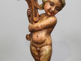 une statue représentant un enfant tenant une harpe posée sur une table