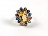 une bague ornée d'une pierre jaune entourée de pierres multicolores