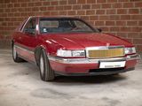 a red car that is parked in front of a brick wall