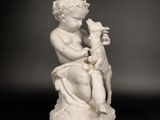 statue d'un garçon avec un chien posée sur une surface réfléchissante