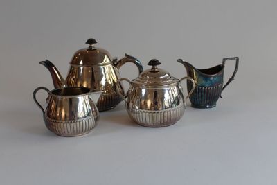 three silver teapots and a pitcher on a table