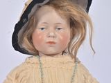a doll that is wearing a dress and a hat