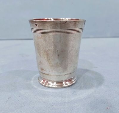 an old silver cup with a handle sitting on a table