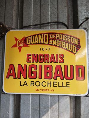 yellow and red sign hanging on a metal wall in a garage