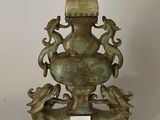 un vase en bronze surmonté d'un oiseau