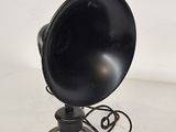 an old fashioned black speaker on a metal stand on a white surface