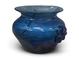 un vase bleu posé sur une surface blanche