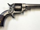 un vieux revolver avec une poignée en bois sur une surface blanche