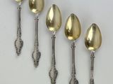 six silver spoons are lined up in a row on a white surface