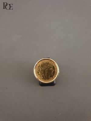 une pièce d'or posée sur une table, à côté d'un objet noir