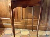 une petite table en bois avec un plateau en verre, posée sur un sol carrelé