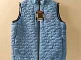 blue quilted vest hanging on a hanger on a wall