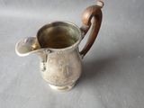 a silver pitcher with a wooden handle sitting on a table