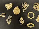 a lot of gold brooches and brooches on a black surface