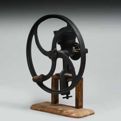 une machine à coudre à l'ancienne posée sur un support en bois, sur un fond gris