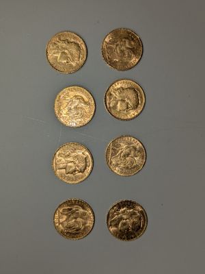 Plusieurs pièces d'or sont alignées sur une surface grise