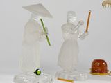 three figurines of people with umbrellas on a white surface