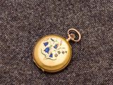 une petite montre de poche en or ornée d'une fleur bleue