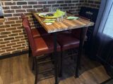 une petite table avec deux chaises rouges et un mur de briques en arrière-plan