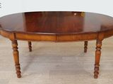 une table à manger ovale aux pieds tournés, posée sur un parquet
