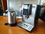 une machine à café argentée posée sur une table à côté d'une cafetière argentée