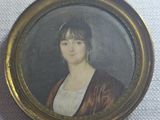 an old picture of a woman in a brown coat is shown in a gold frame