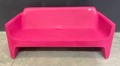 un banc en plastique rose posé sur un sol en béton