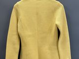 une veste jaune suspendue à un cintre devant un mur gris