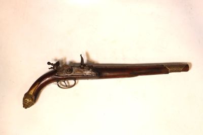 un vieux pistolet avec une poignée en bois sur une surface blanche