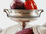 a silver plate with a bowl of vegetables on top of it