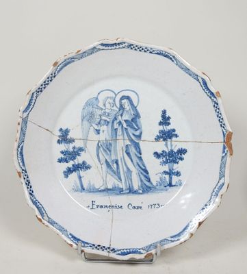 une vieille assiette bleue et blanche sur laquelle est représenté un ange