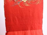 a red dress with a bird on it hanging on a wall