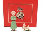 une petite figurine représentant une femme et un chien devant une boîte rouge