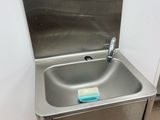 a stainless steel sink in the corner of a bathroom