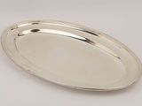 an oval silver tray with a handle on a white surface