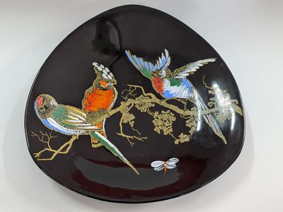 a black plate with birds painted on it on a table
