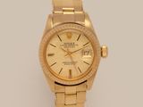 an image of a gold rolex watch on a white surface