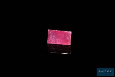 the pink soap bar is sitting on a black surface