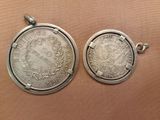 two silver coin pendants, one with a crown and the other with a wreath