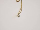 a close up of a gold chain with a small diamond on it