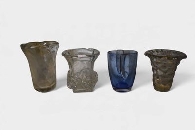 quatre vases en verre de couleurs différentes posés les uns à côté des autres sur une surface blanche