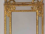 miroir à cadre doré aux motifs ouvragés accroché à un mur blanc