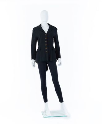 Le mannequin porte un costume noir et un pantalon noir.