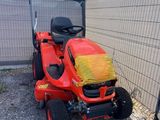 une photo d'une tondeuse à gazon rouge garée devant une clôture