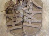 tan leather sandals with laces on the toes of them on a wooden floor