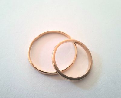 two gold wedding rings on a white surface
