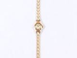 a gold watch on a white surface with a chain around it