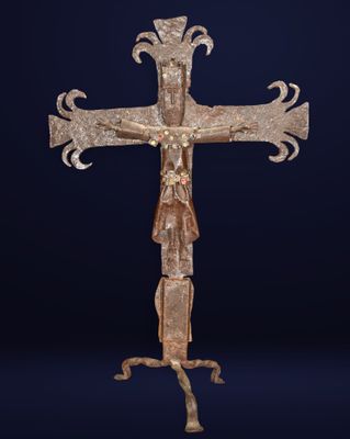 une vieille croix en métal posée sur un socle, sur fond bleu